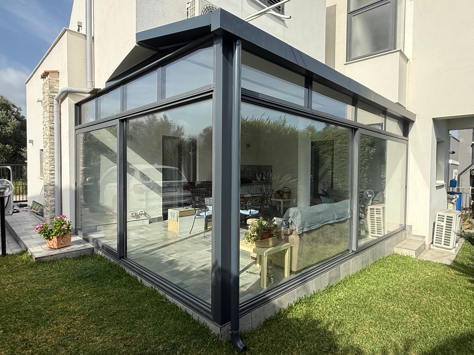 Giardino d'inverno in alluminio antracite ad angolo con vetrate fisse e scorrevoli