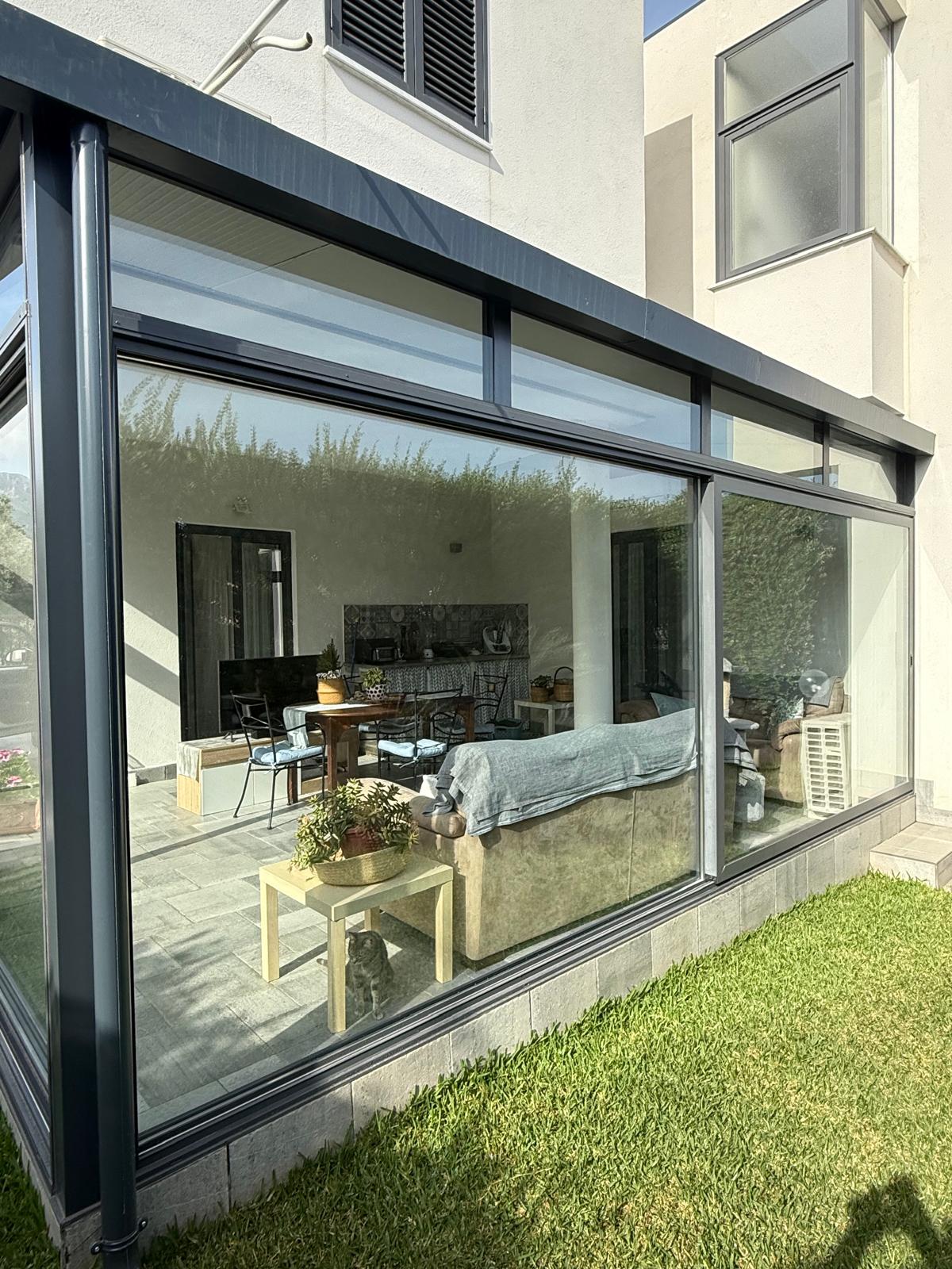 Veranda in alluminio antracite con vetrate scorrevoli a tutta altezza, vista giardino